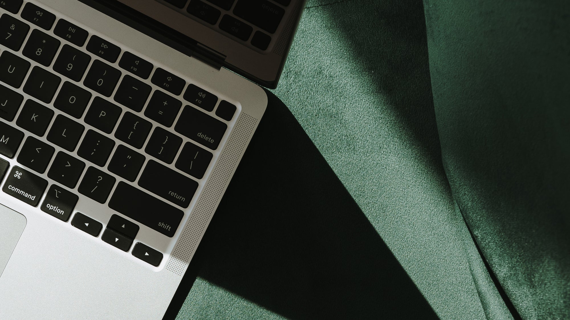 Flat lay of a laptop on green velvet surface, symbolizing modern marketing work environment for service-based businesses by MBL Marketing