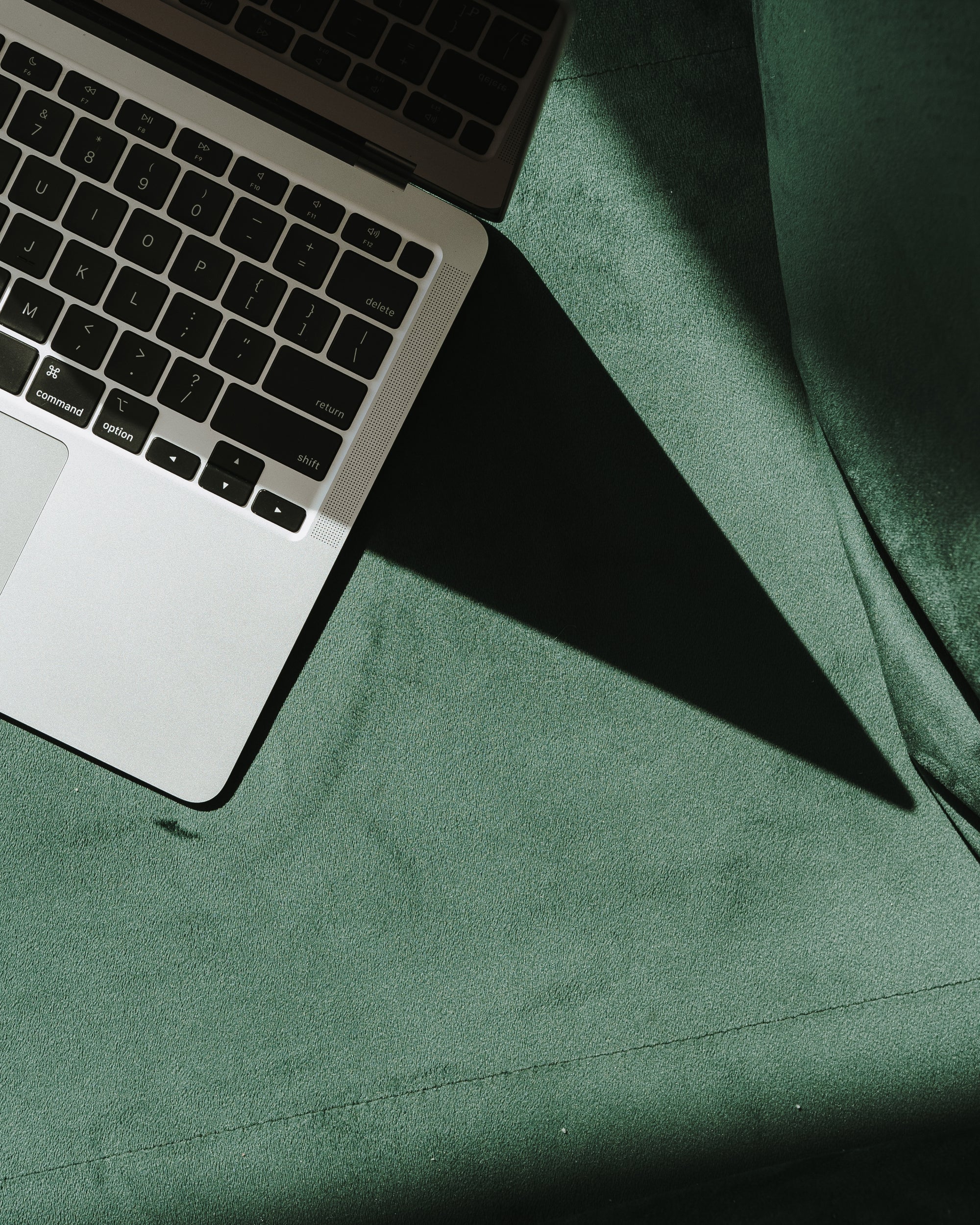 Flat lay of a laptop on green velvet surface, symbolizing modern marketing work environment for service-based businesses by MBL Marketing